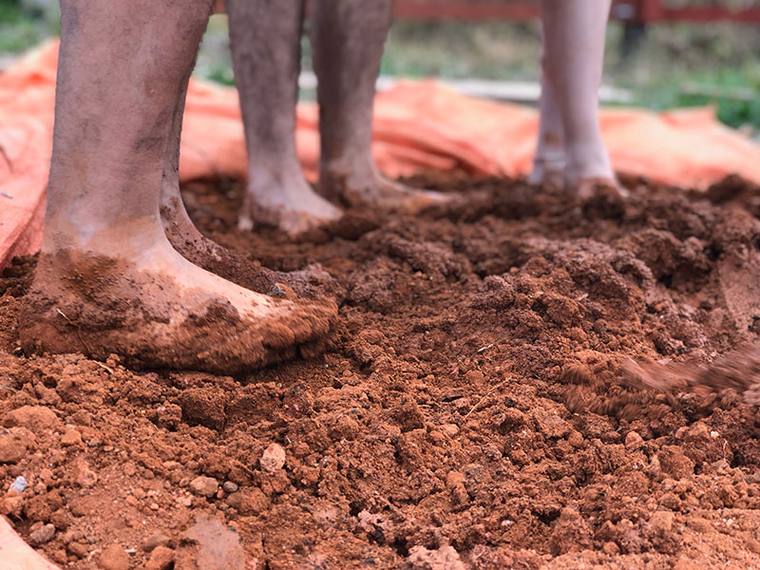 Bare feet standing in freshly turned red soil.