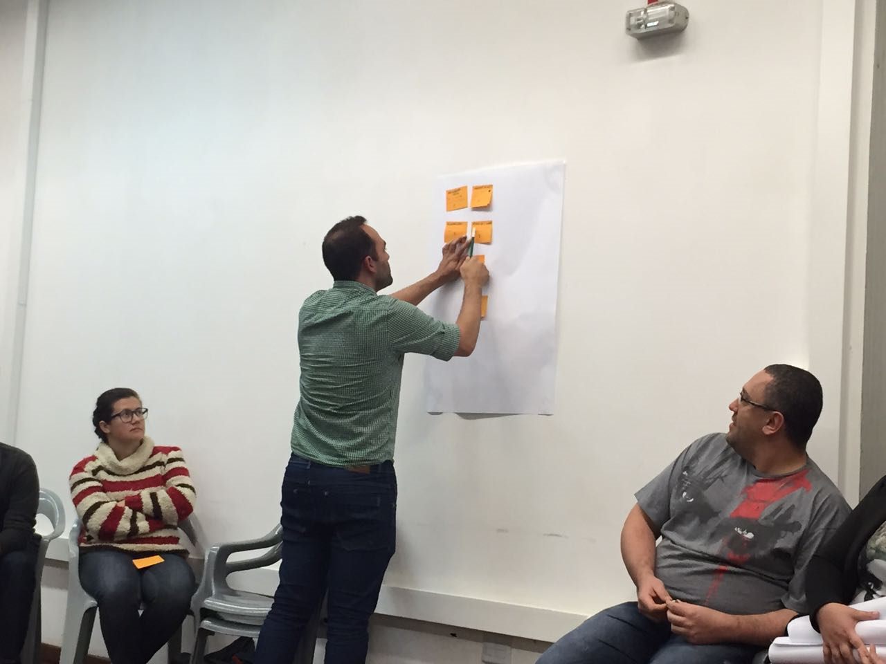 Daniel placing notes on a wall during a workshop.